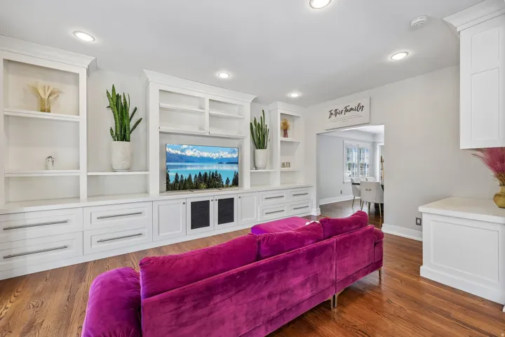 Custom built-in shelving with integrated media center, recessed lighting, and rich wood-finish flooring