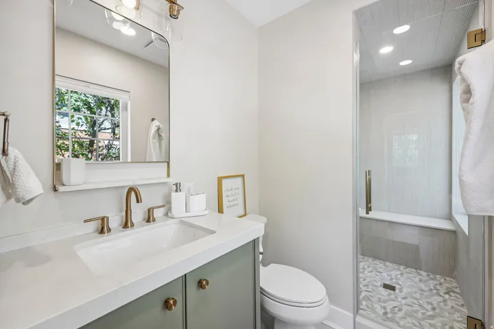 Vanity with green cabinetry, white rectangular sink, and bronze-finish fixtures