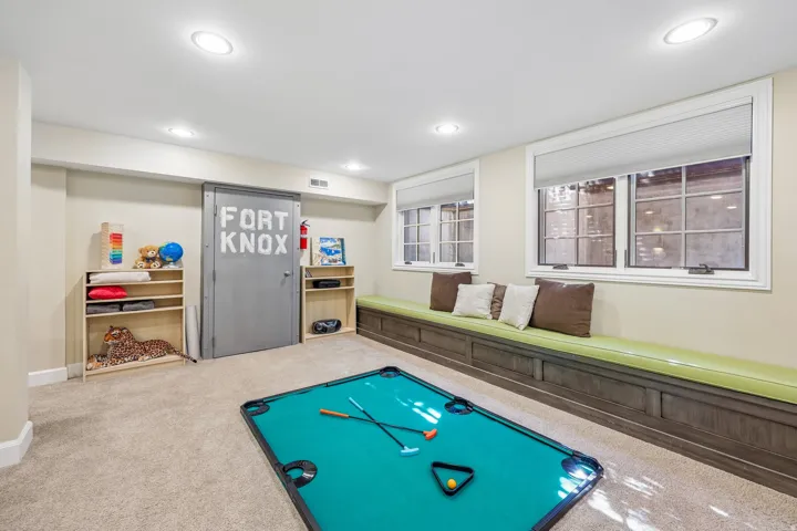 Recessed lighting, two windows with blinds, built-in window seating with cushion, two built-in shelving units, and carpet flooring