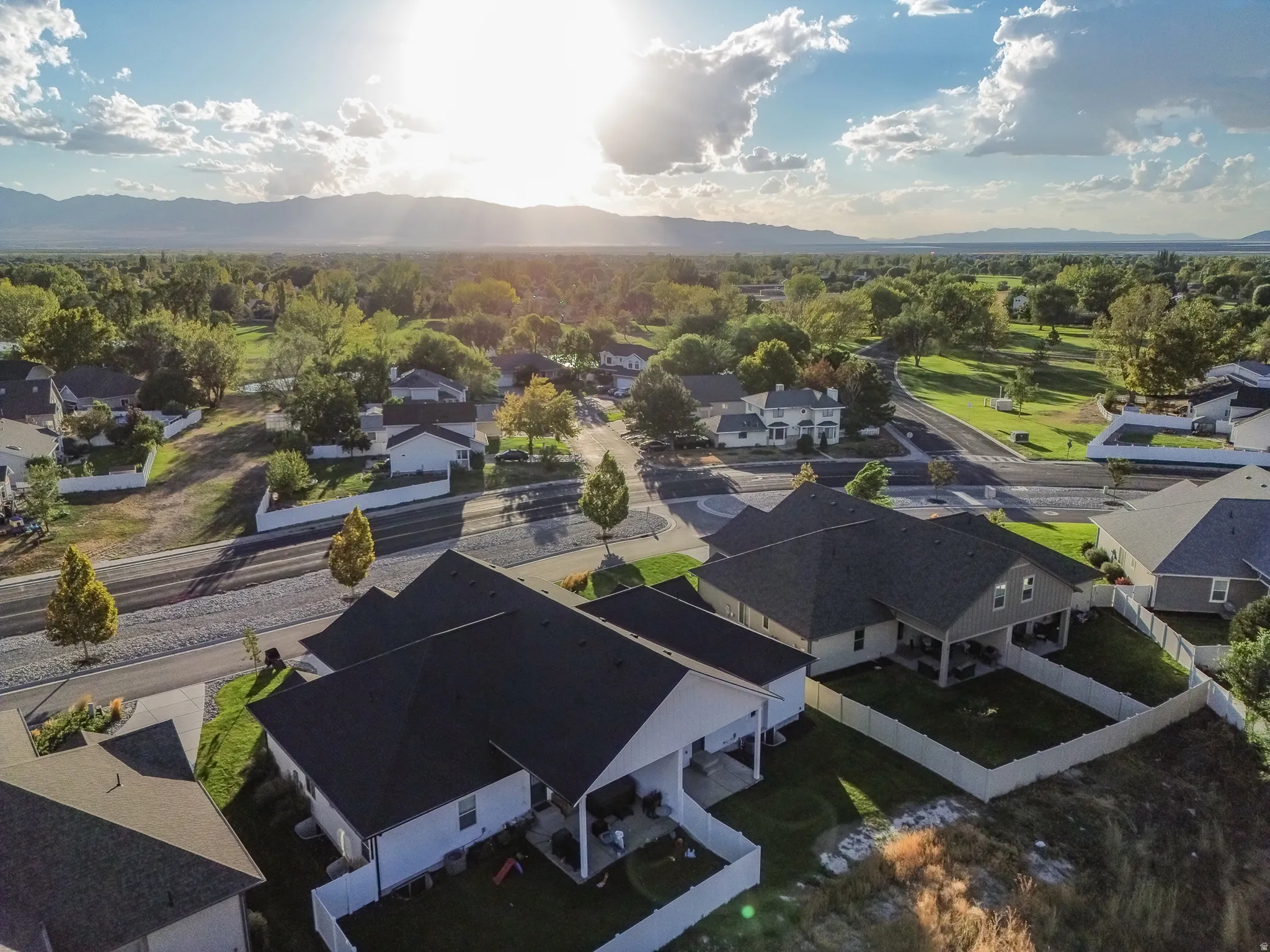 Residential community featuring single-family homes, mature trees, and mountainous distant scenery