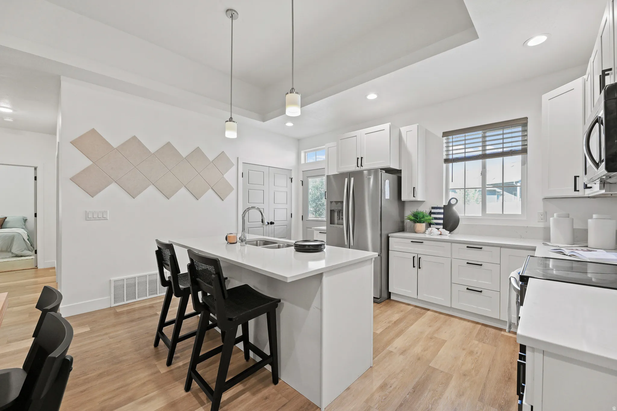 Contemporary kitchen featuring light wood-finish flooring, white cabinetry, and stainless steel appliances