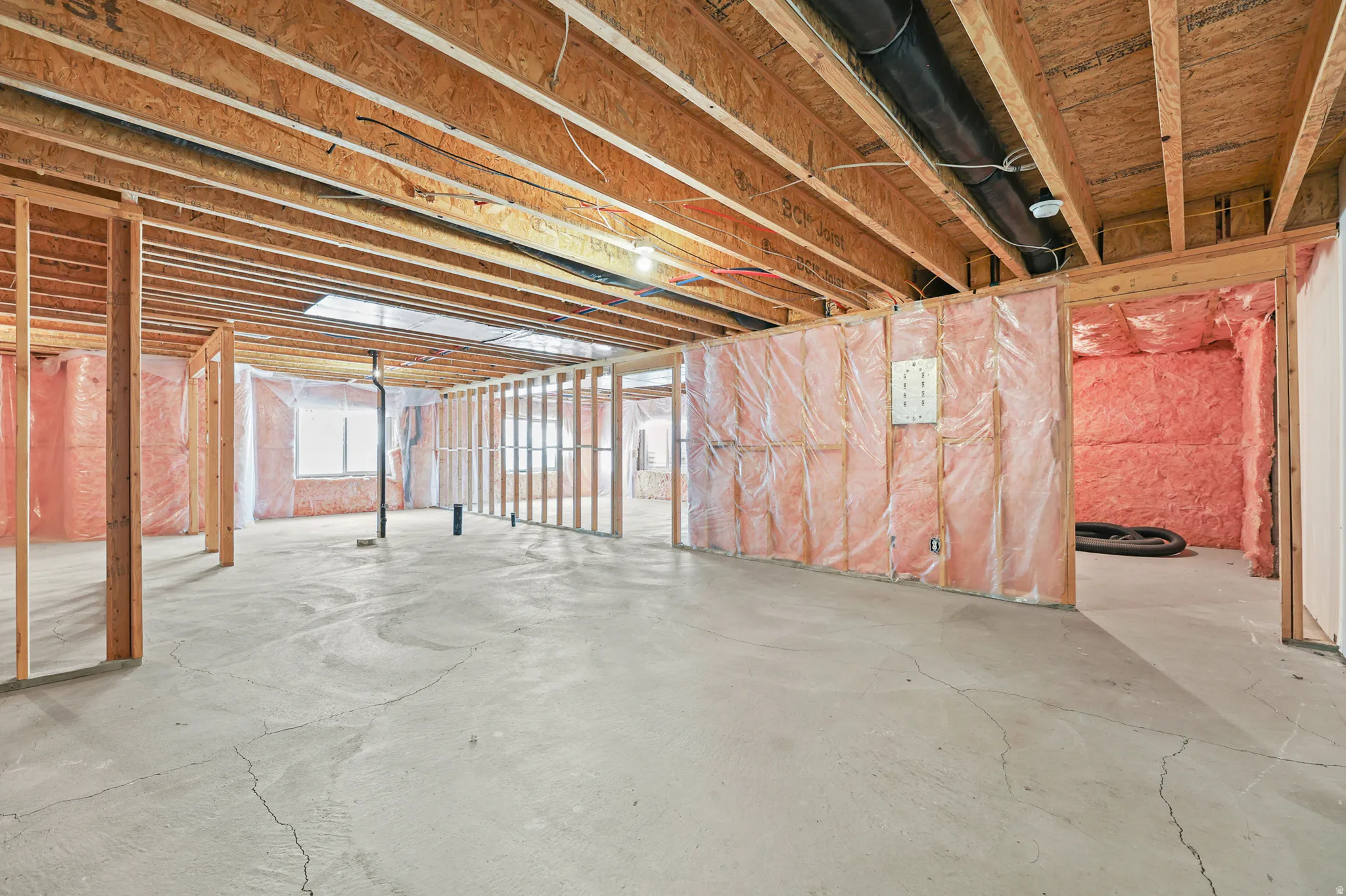 Unfinished basement featuring exposed wood framing, concrete flooring, and ceiling joists