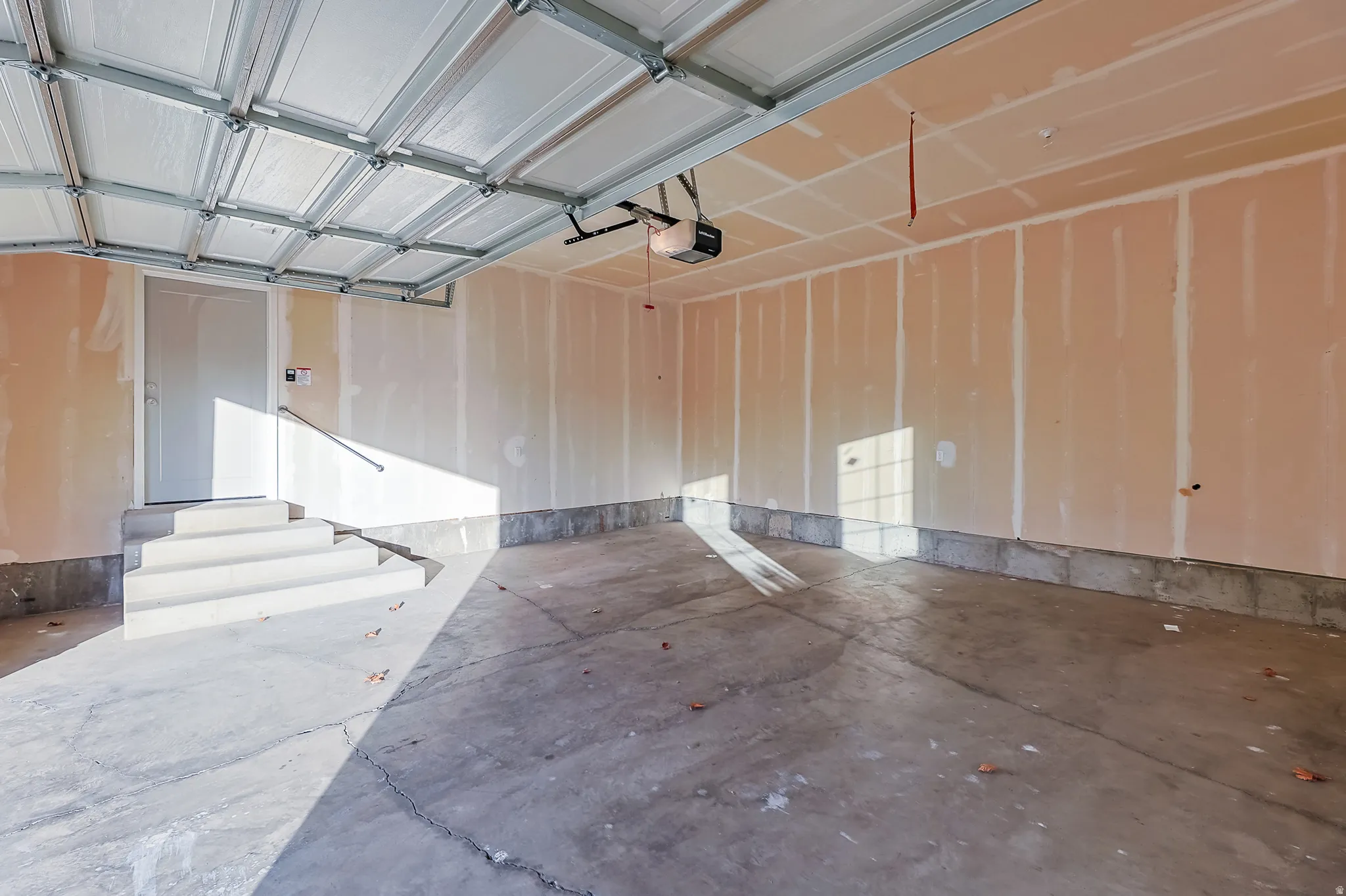 Concrete flooring, white interior door, light brown drywall, built-in handrail, automatic garage door opener