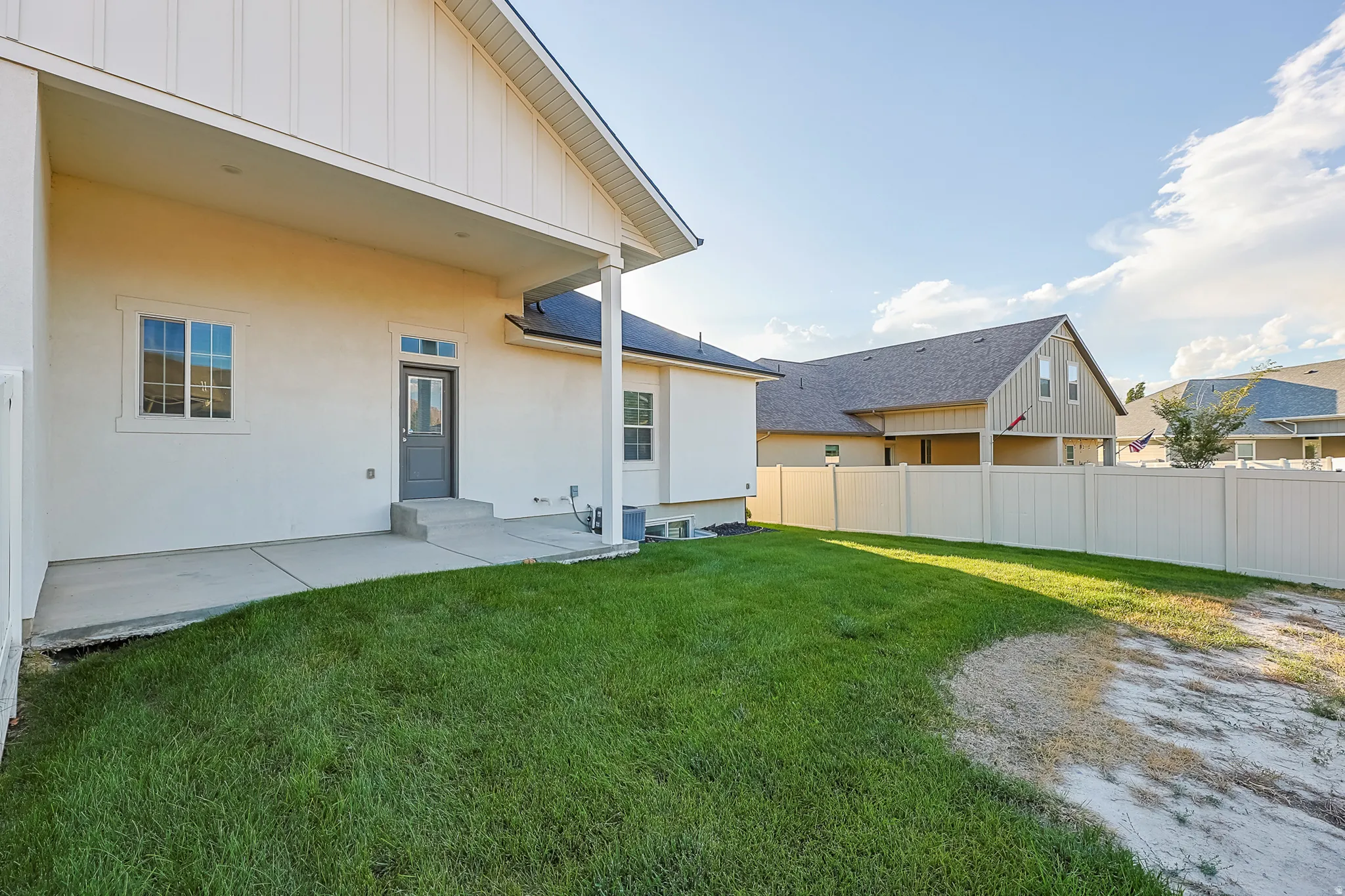 Covered patio with concrete flooring, white stucco exterior, and a privacy fence