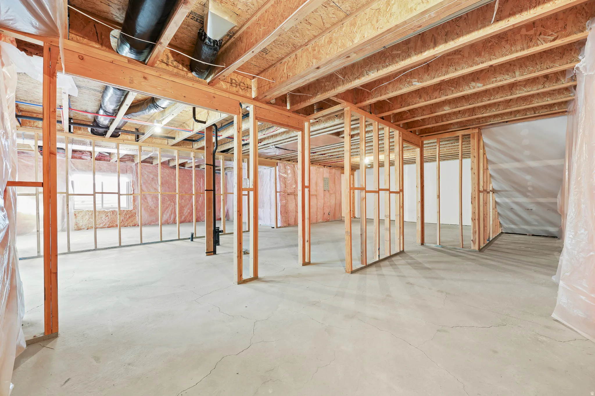 Unfinished basement with concrete flooring, exposed wood framing, and visible ductwork