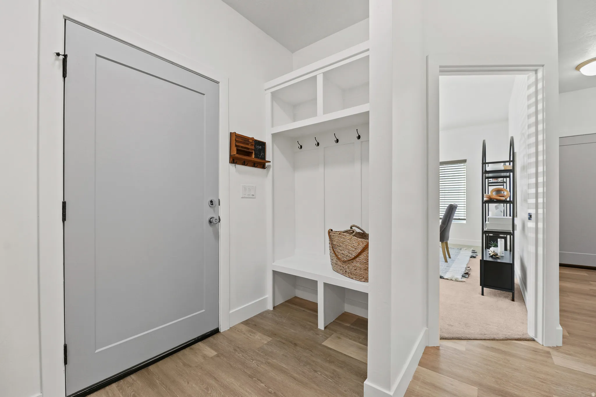 Built-in storage bench with upper shelving, matte black coat hooks, and wood-finish flooring