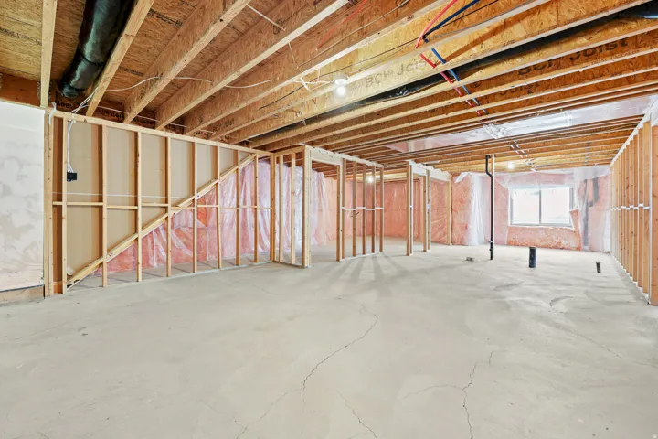 Unfinished basement offering exposed wood framing, wood ceiling joists, and a concrete floor