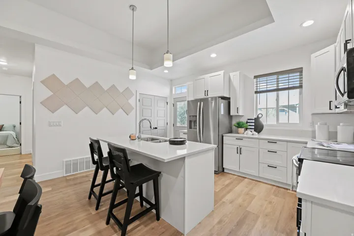 Contemporary kitchen featuring light wood-finish flooring, white cabinetry, and stainless steel appliances