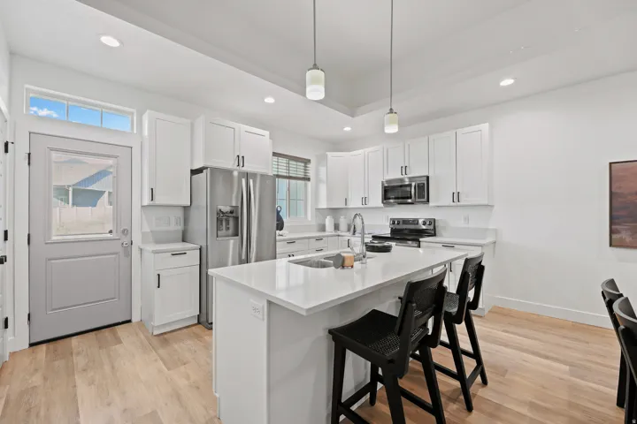 Modern kitchen featuring white shaker cabinetry, stainless steel appliances, a center island with counter seating, wood-finish flooring, and recessed lighting