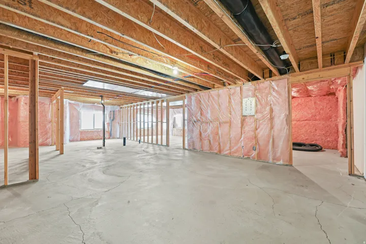 Unfinished basement featuring exposed wood framing, concrete flooring, and ceiling joists