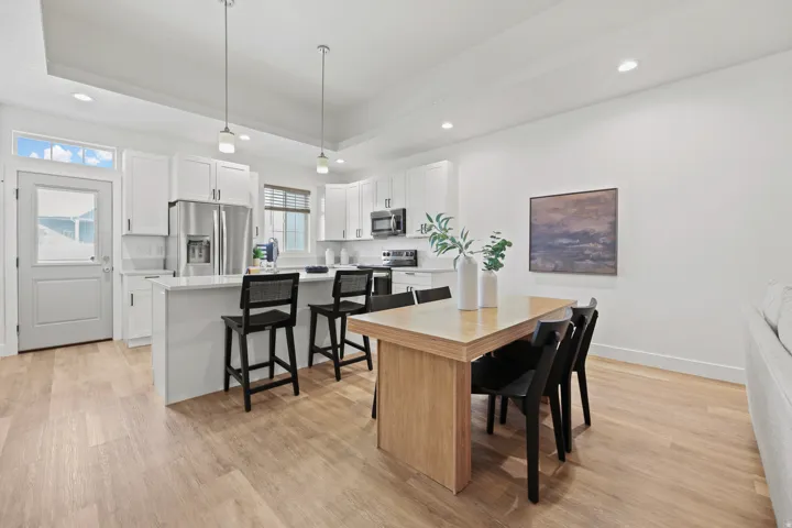 Open-concept kitchen and dining area featuring light wood-finish flooring, white cabinetry, a kitchen island with seating, and recessed ceiling lighting