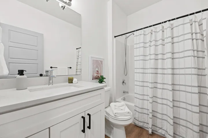 Bathroom #2. Main Bathroom. White shaker-style vanity with dark hardware, integrated countertop and sink, chrome single-handle faucet, and wood-finish flooring