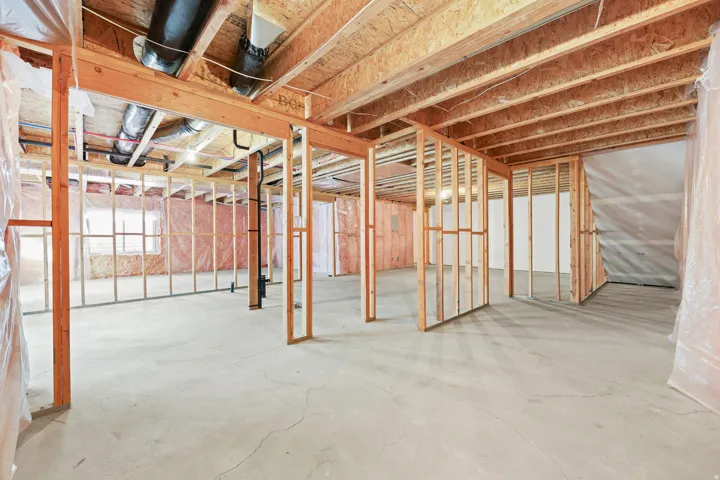 Unfinished basement with concrete flooring, exposed wood framing, and visible ductwork