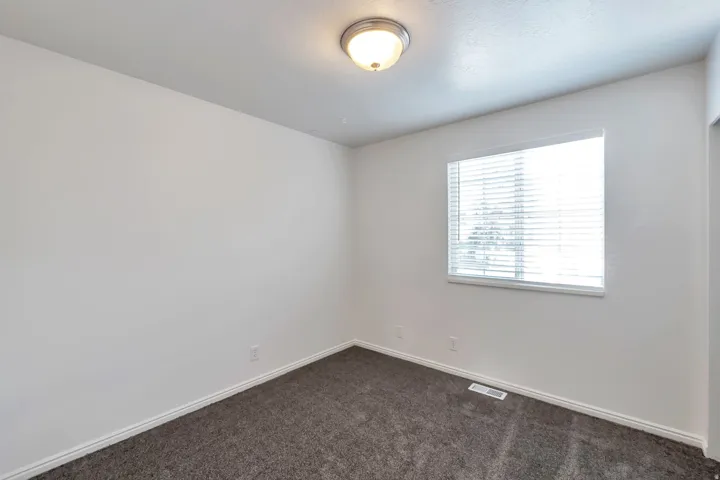 Interior room with gray carpet, a single window with blinds, and a flush-mount ceiling light