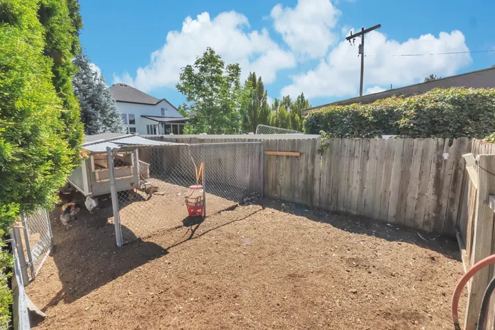 Enclosed outdoor space featuring a wood fence, chain-link fencing, and wood-mulch ground covering