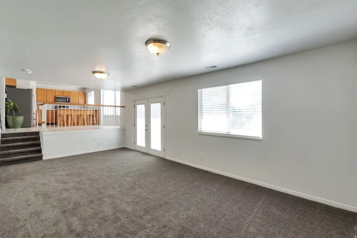 Open-concept living space featuring neutral carpeting and white wall finishes