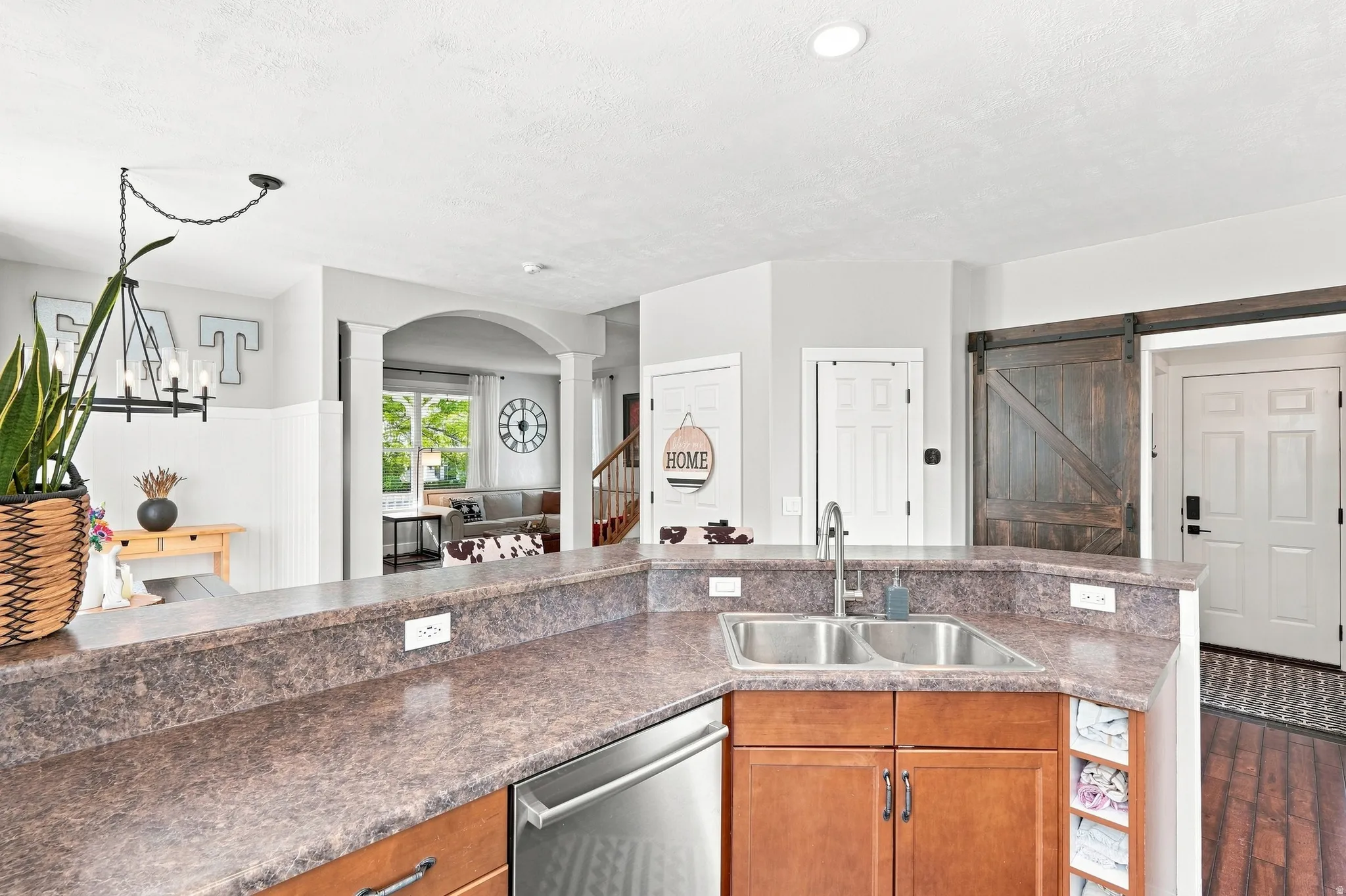 Kitchen featuring a double basin sink, stainless steel dishwasher, wood-finish cabinetry, and laminate countertops