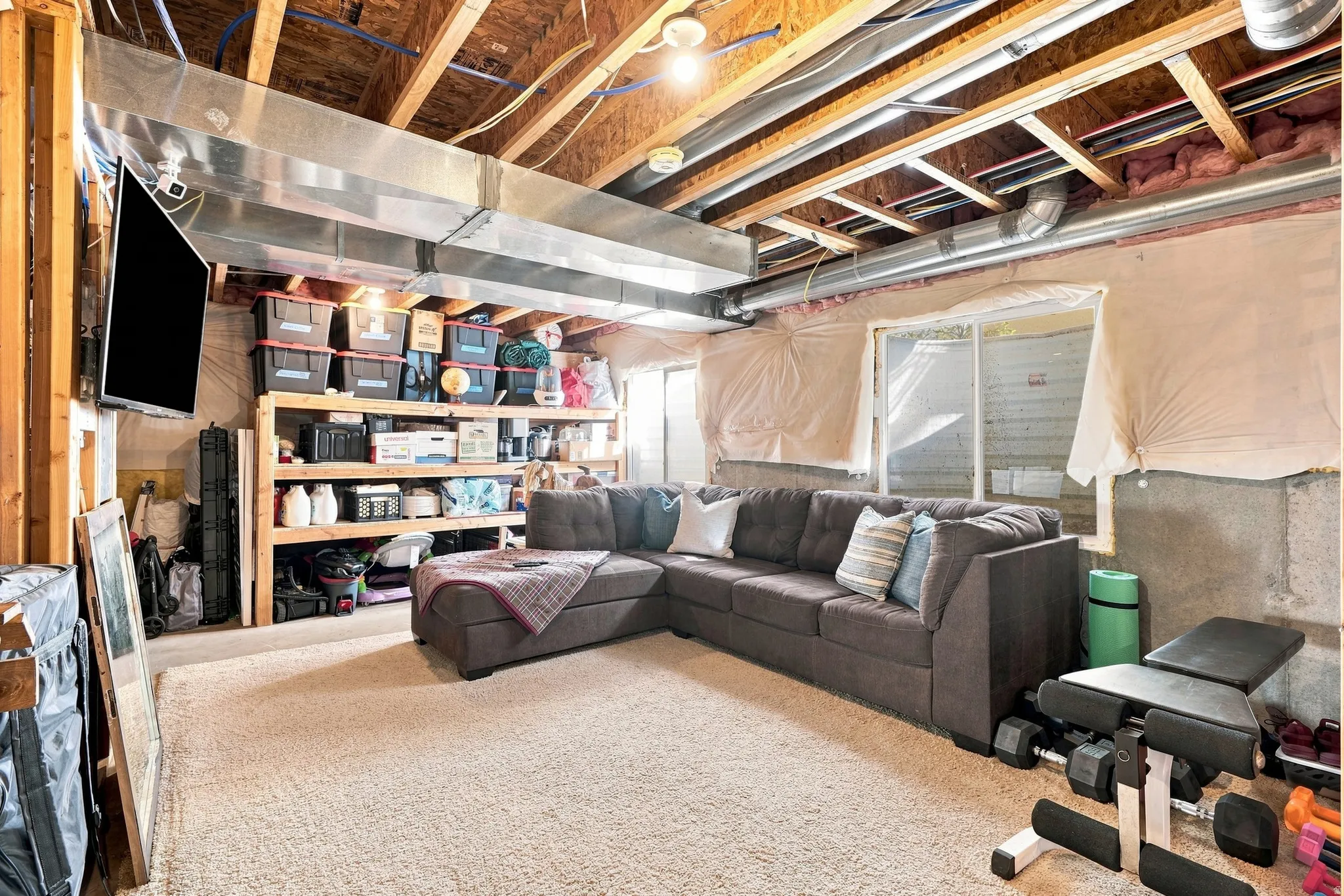 Daylight basement featuring exposed ceiling joists, ductwork, and a built-in window