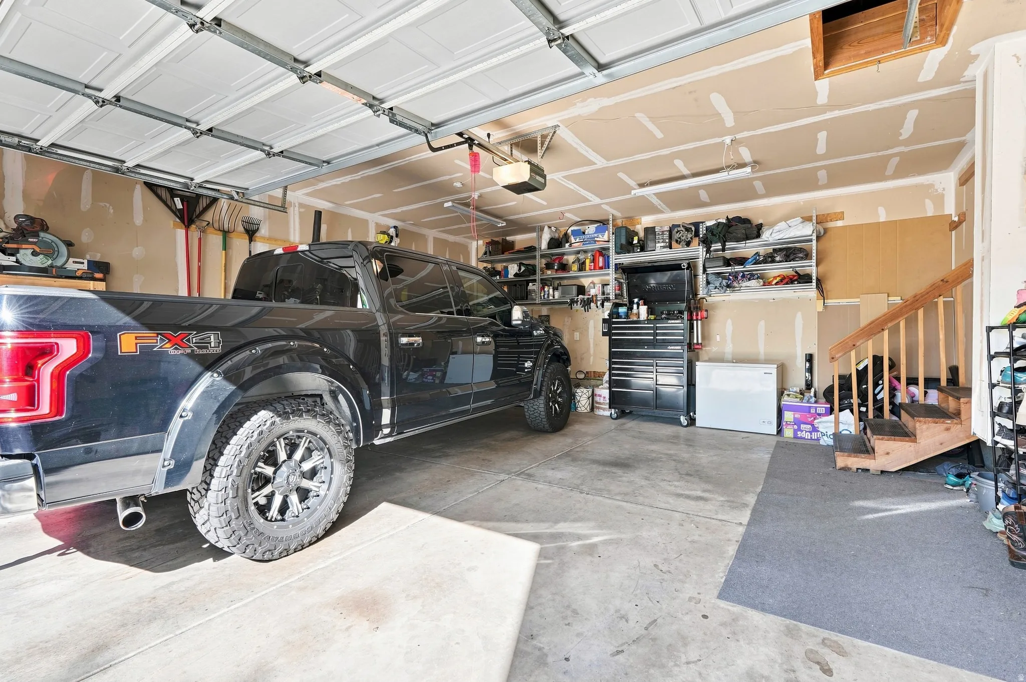 Attached garage featuring a panel garage door, concrete flooring, and built-in shelving