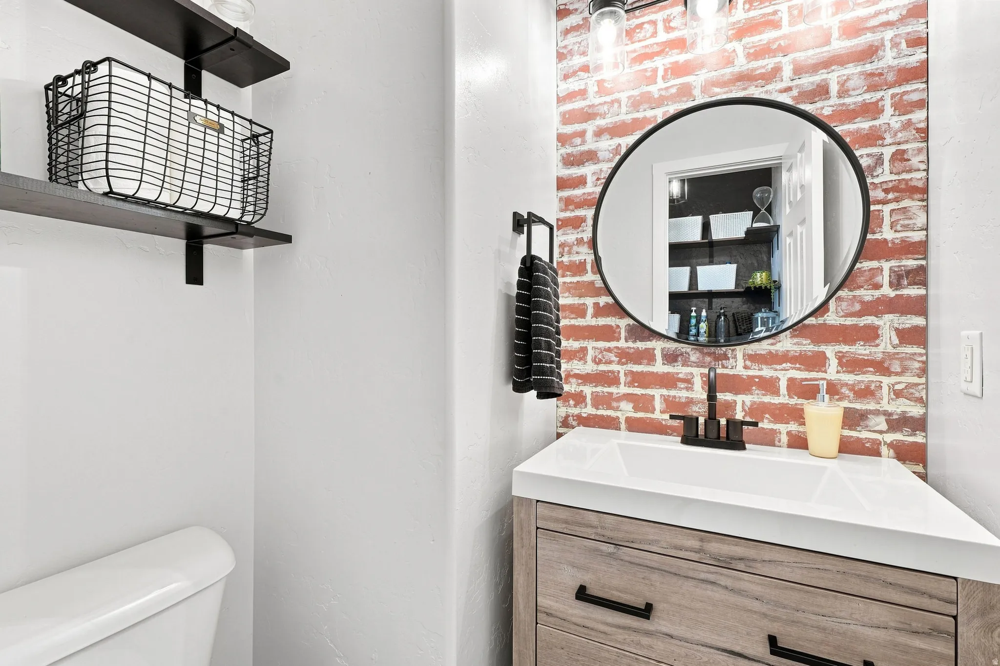 Wood-finish vanity with a white countertop sink and matte black faucet
