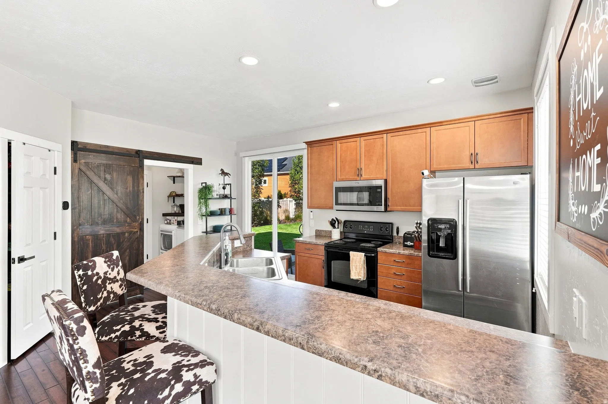Kitchen featuring a large breakfast bar, stainless steel appliances, wood cabinetry, and a sliding glass door to the exterior