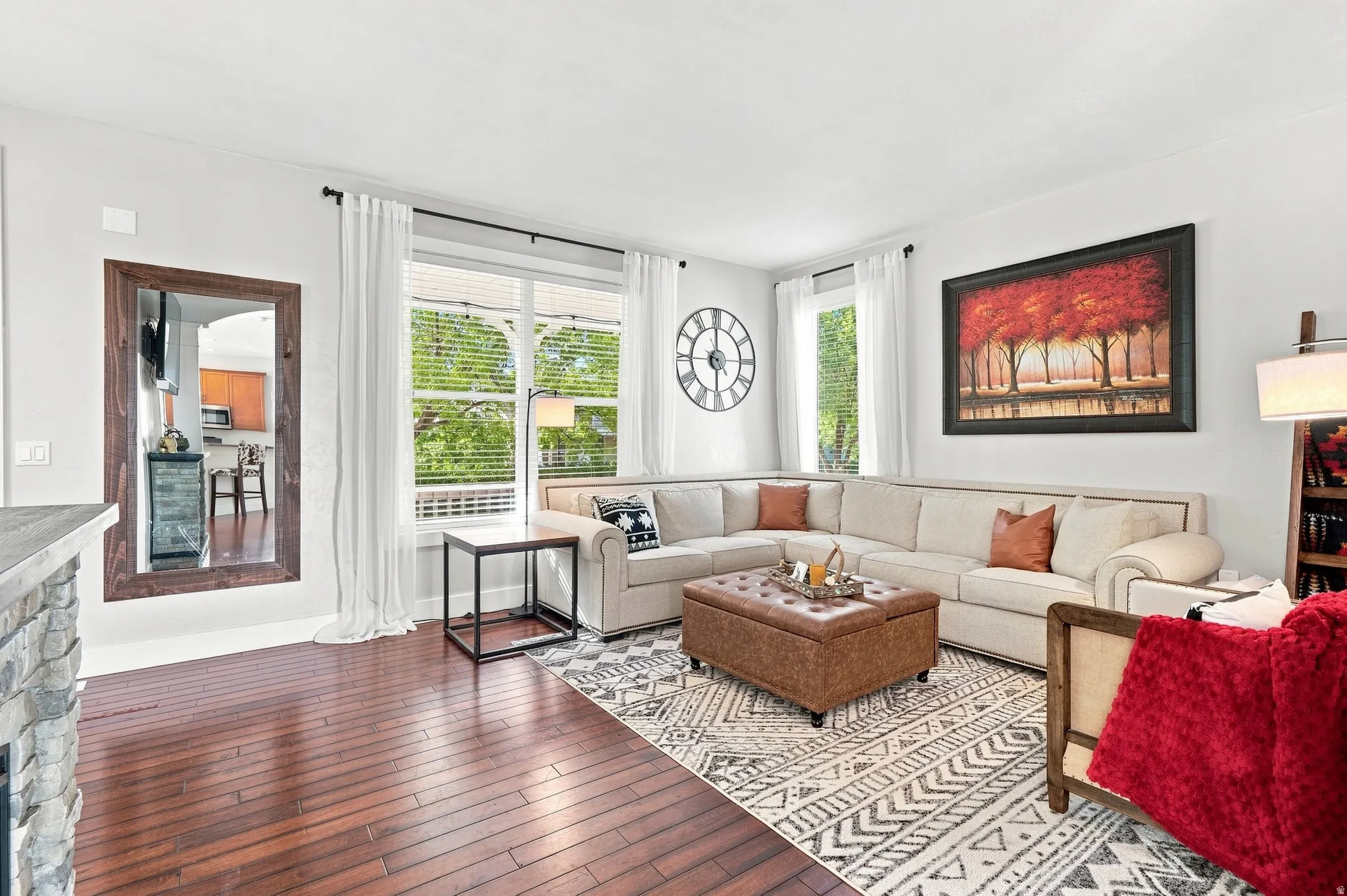 Rich wood-finish flooring, extensive natural light, stone-clad half wall, and a large wall-mounted mirror