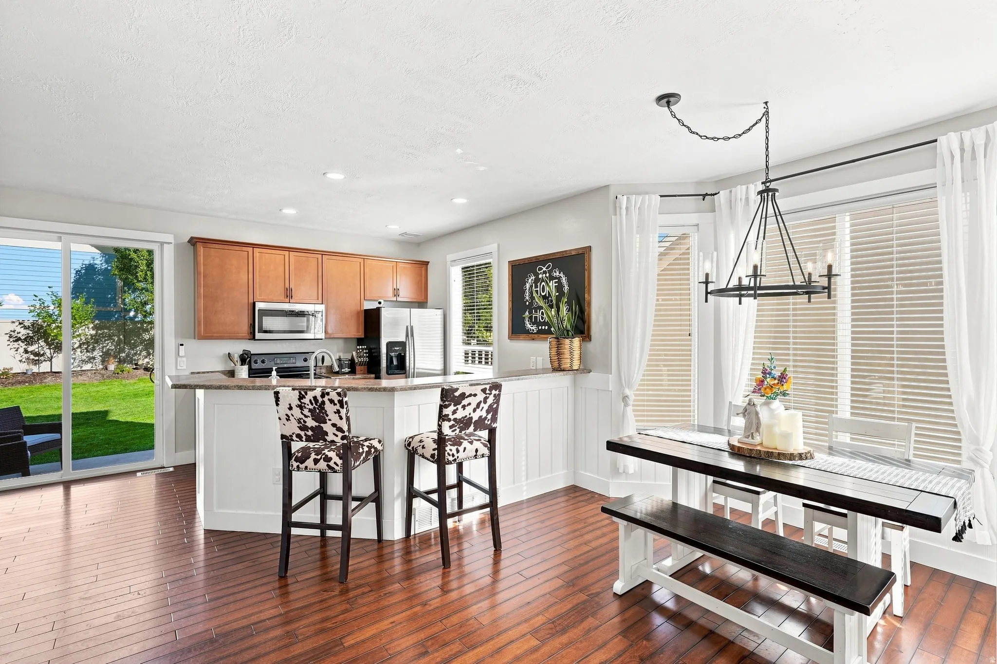 Wood-finish flooring throughout, kitchen island with built-in cabinetry, stainless steel appliances, and a sliding glass door