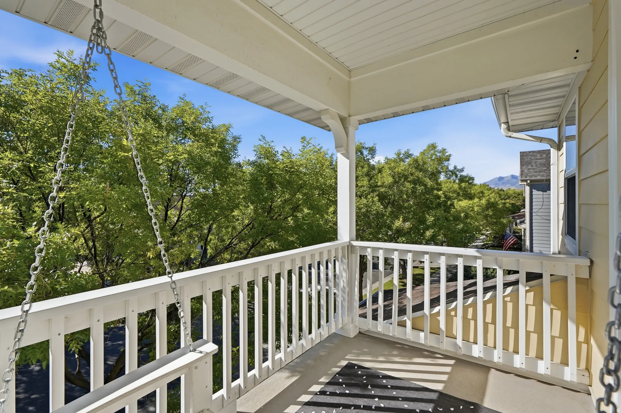 Covered balcony featuring white railing and a mountain backdrop
