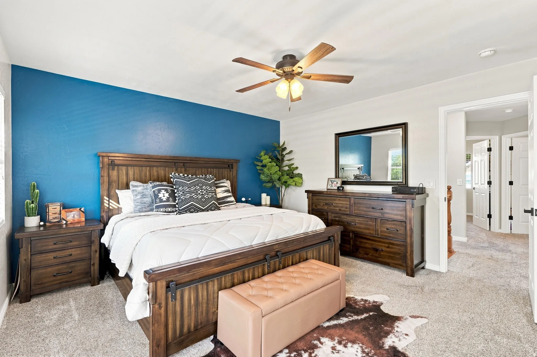 Spacious room with a blue accent wall, neutral carpeting, and a ceiling fan