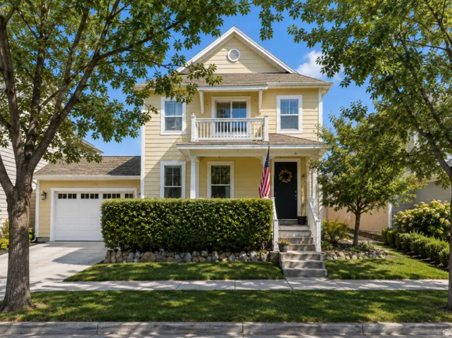 **AI generated** photo to be able to view this beautiful two-story residence with light-yellow siding, a white garage door, and a second-story balcony. (windows are not exact.)