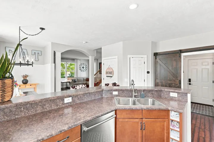 Kitchen featuring a double basin sink, stainless steel dishwasher, wood-finish cabinetry, and laminate countertops