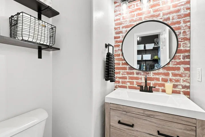 Wood-finish vanity with a white countertop sink and matte black faucet
