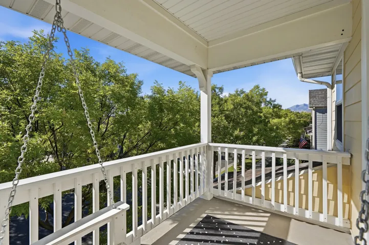 Covered balcony featuring white railing and a mountain backdrop