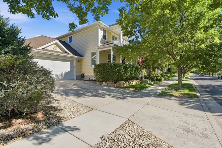 Two-story residence with light yellow siding, attached two-car garage, and a covered front porch