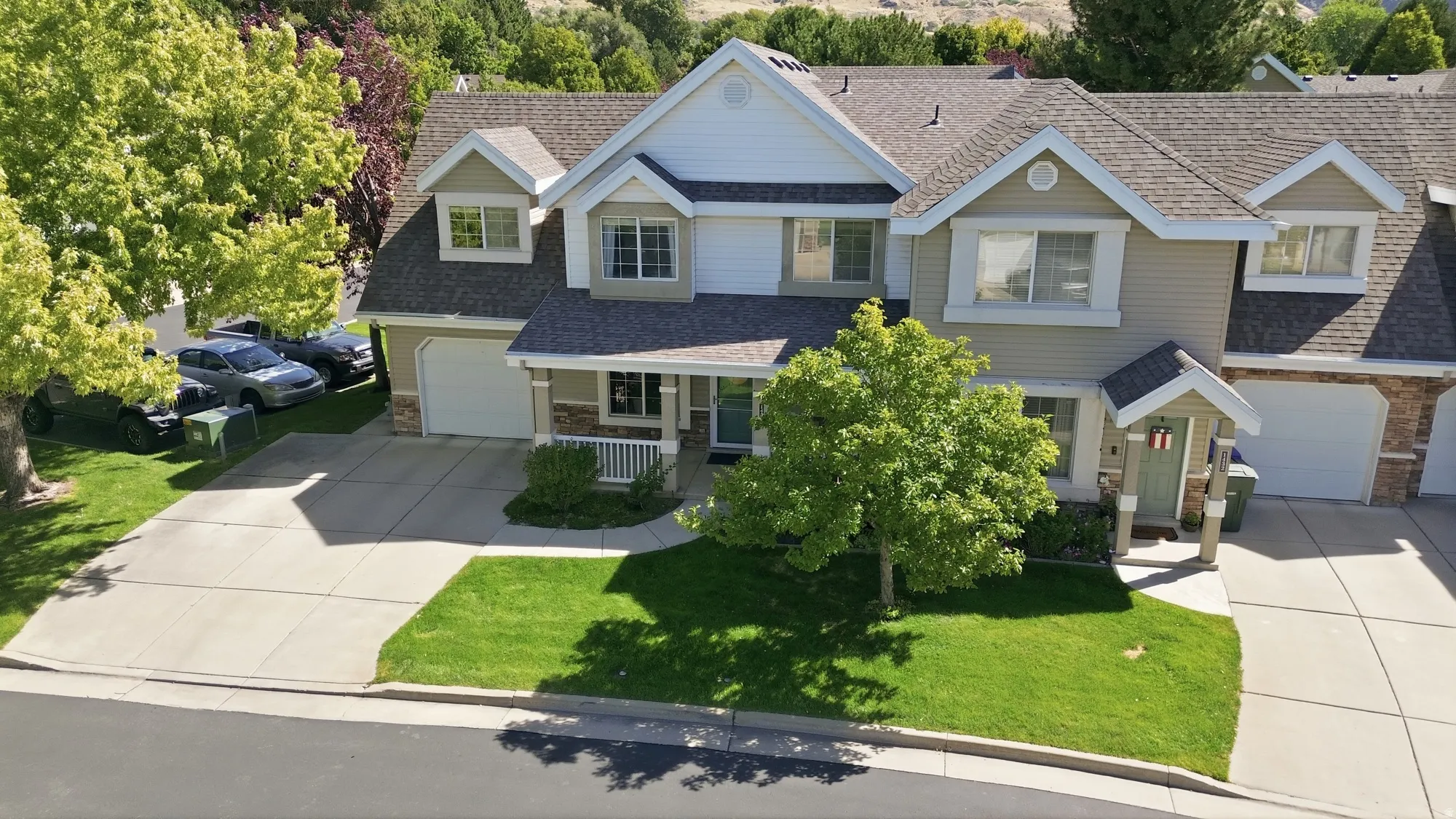 Elevated view of the home highlighting the front exterior, attached garage, mature trees, and surrounding neighborhood.