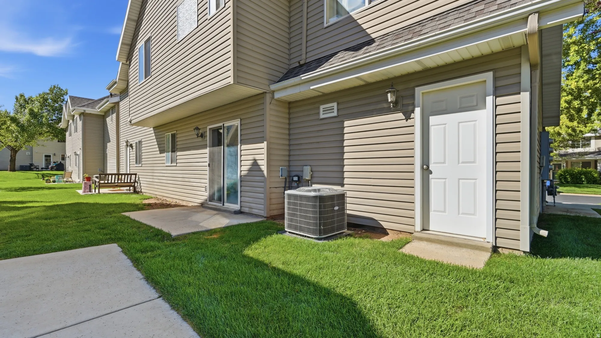 Rear exterior with patio access, mature lawn, and convenient exterior access near the attached garage.