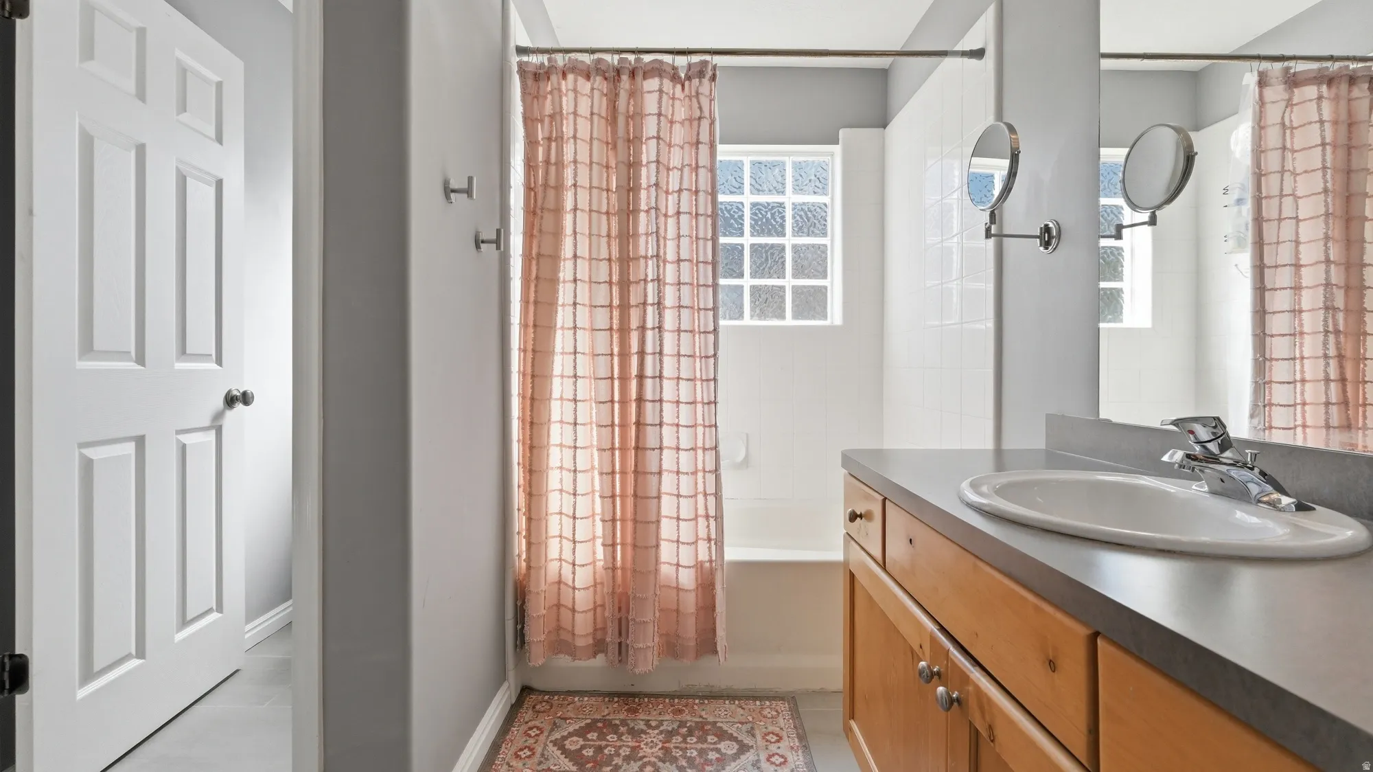 Primary bathroom features a tub/shower combination, vanity storage, large mirror, and a bright window for natural light.