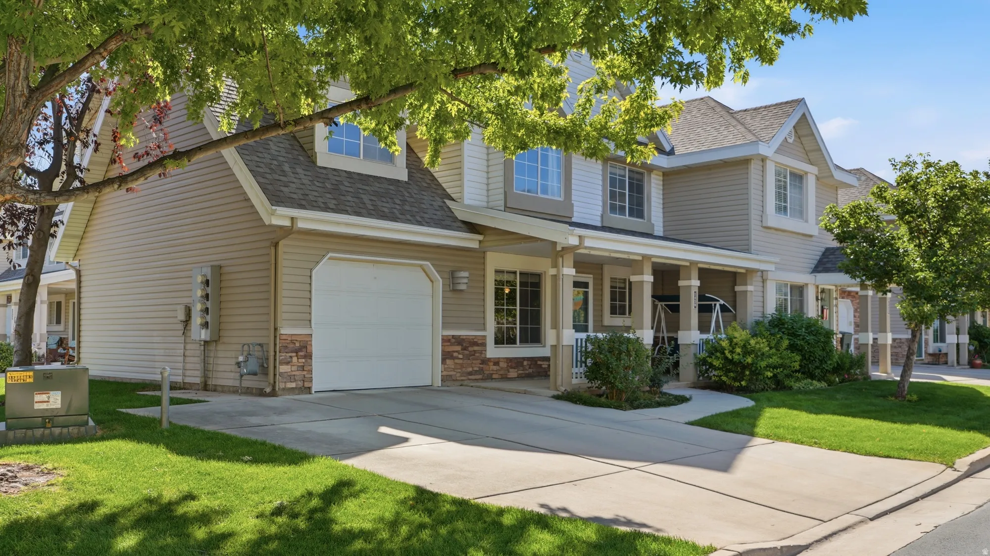 Two-story exterior with attached garage, covered porch, mature trees, and beautifully maintained common landscaping.