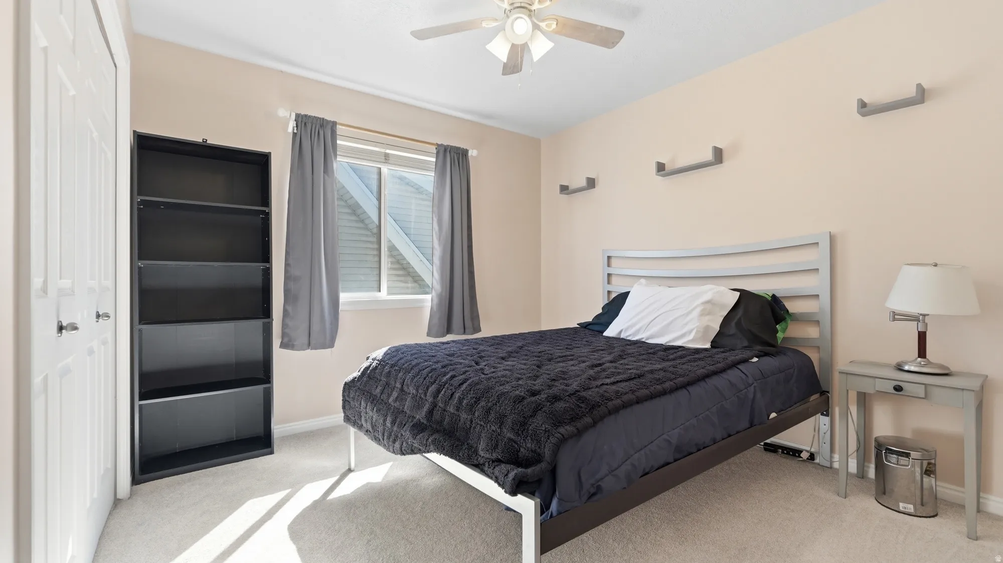 Comfortable bedroom with ceiling fan, large window for natural light, and generous closet space.