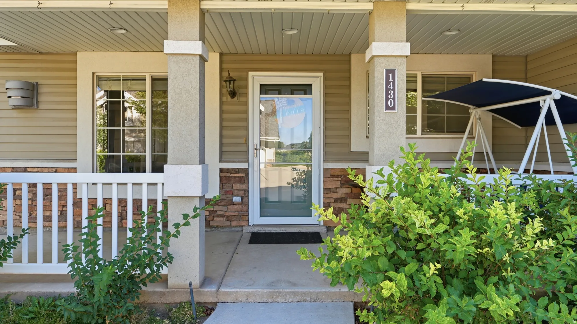 Welcoming front porch with architectural columns and stacked stone accents, complemented by horizontal siding and a full-light storm door