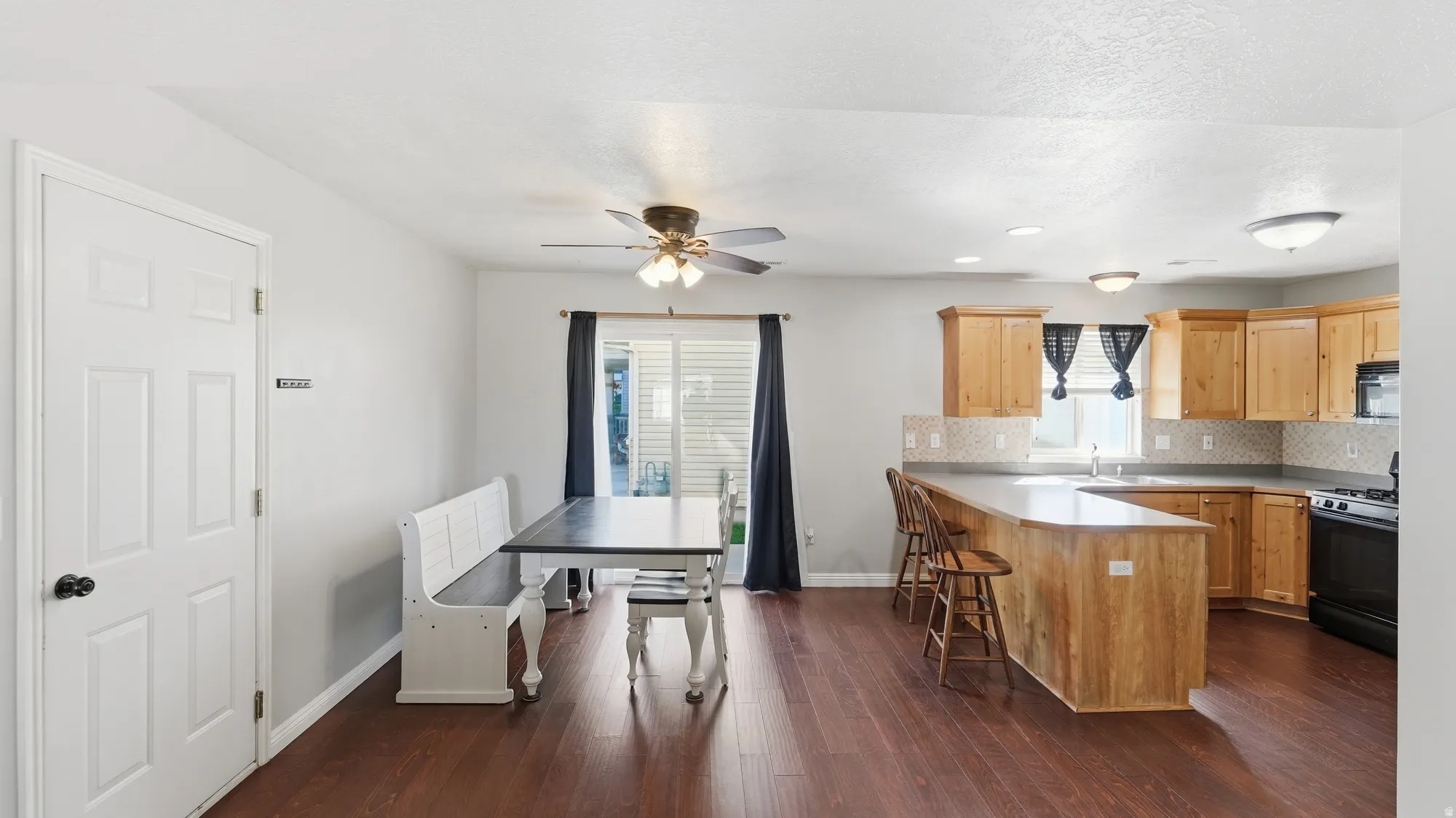 Open kitchen and dining area with beautiful LVP flooring, generous cabinetry, breakfast bar seating, and access to the outdoor patio.