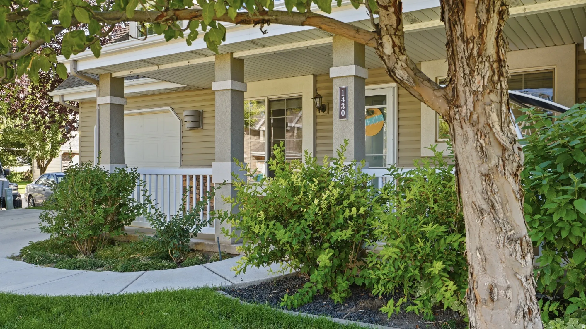 Inviting covered front porch surrounded by mature landscaping and shade trees, creating a welcoming entrance.