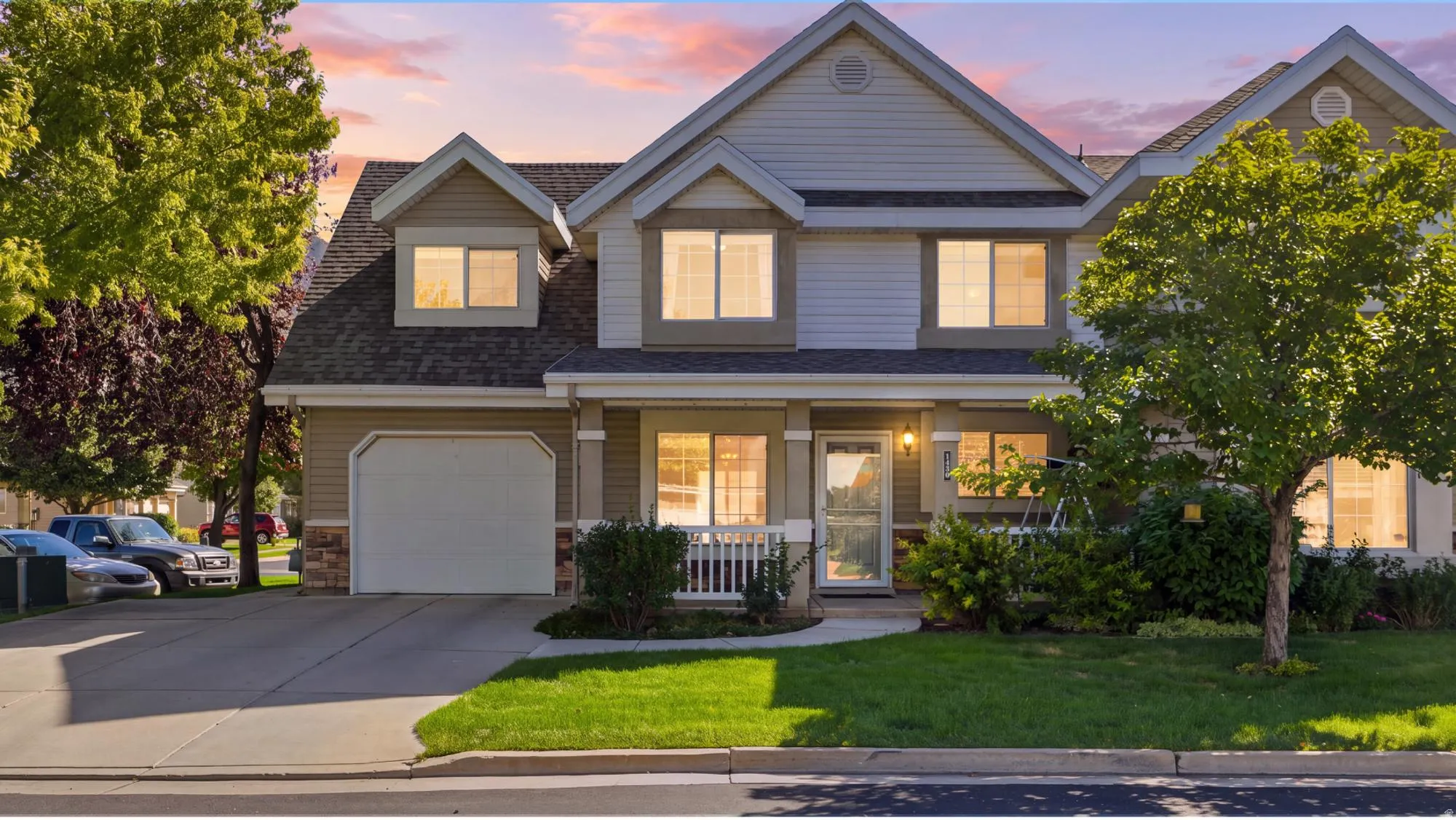 Beautiful twilight exterior showcasing the home’s inviting curb appeal, covered front porch, mature landscaping, and warm evening glow.