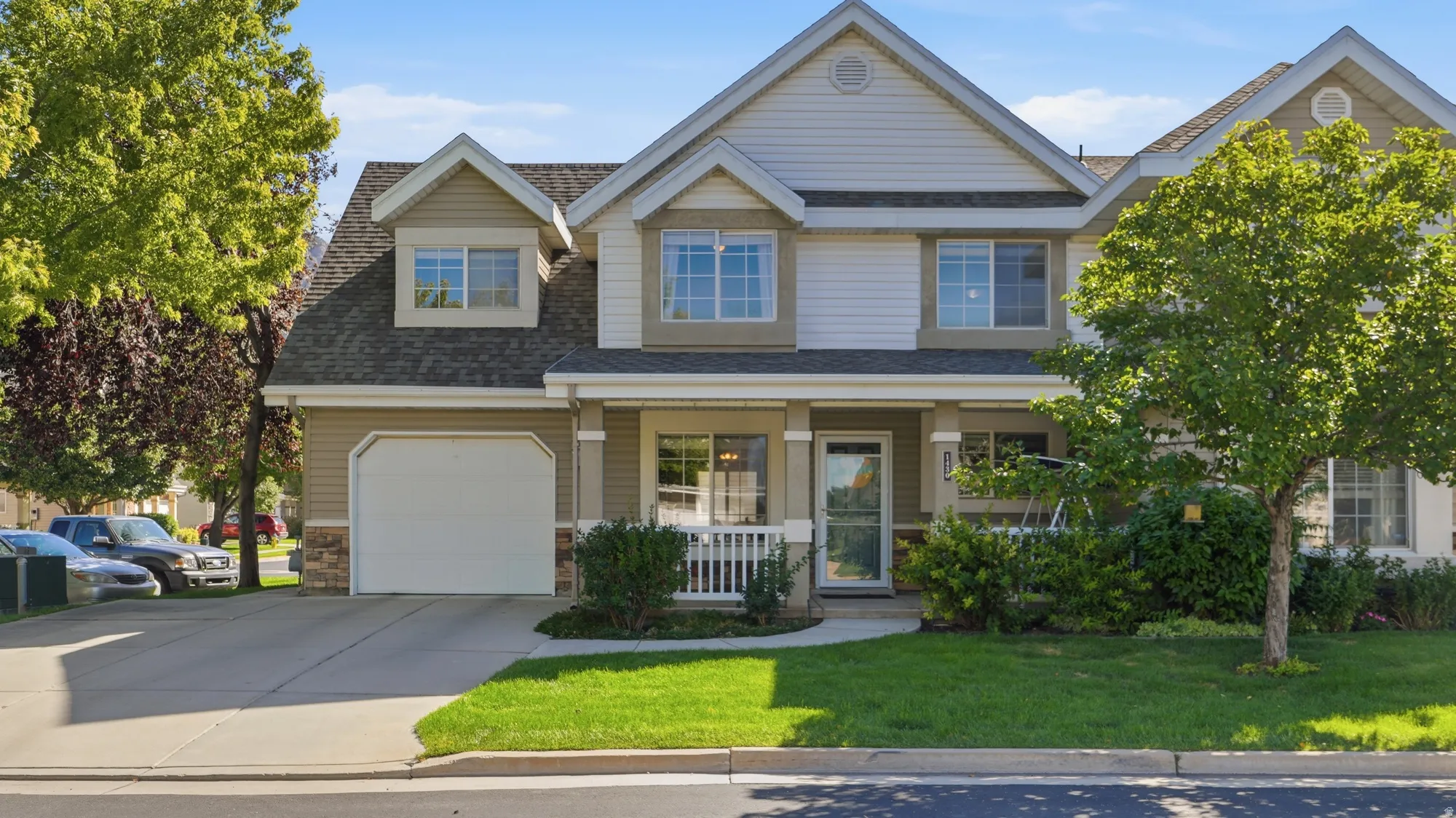 Beautiful two-story residence featuring a covered front porch, attached garage, and a manicured lawn