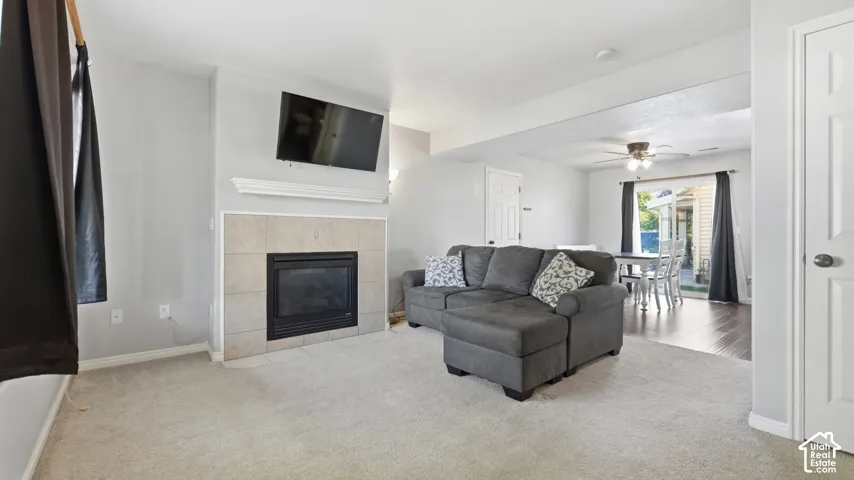 Comfortable main-level living room featuring a cozy fireplace, large windows, and an open flow into the dining and kitchen areas.