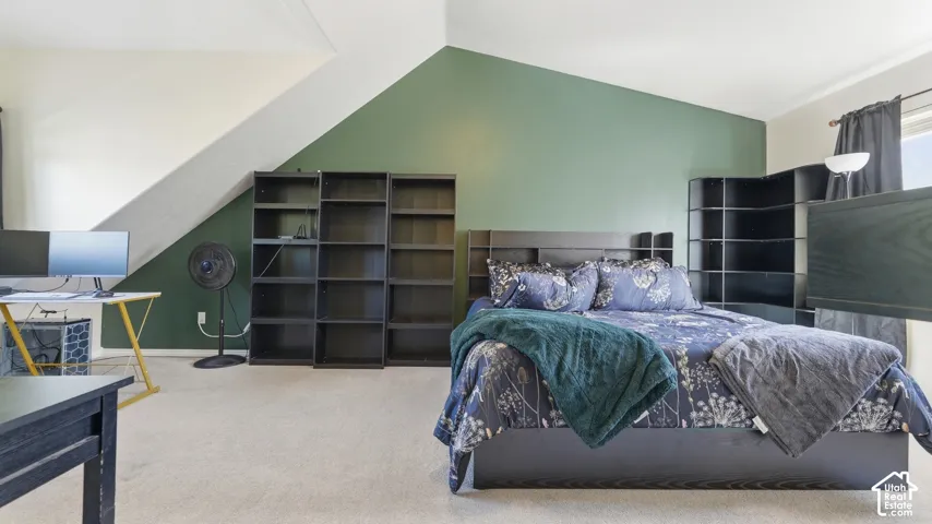 Spacious primary bedroom with vaulted ceiling, abundant floor space, and plenty of room for additional furniture or a home office setup.