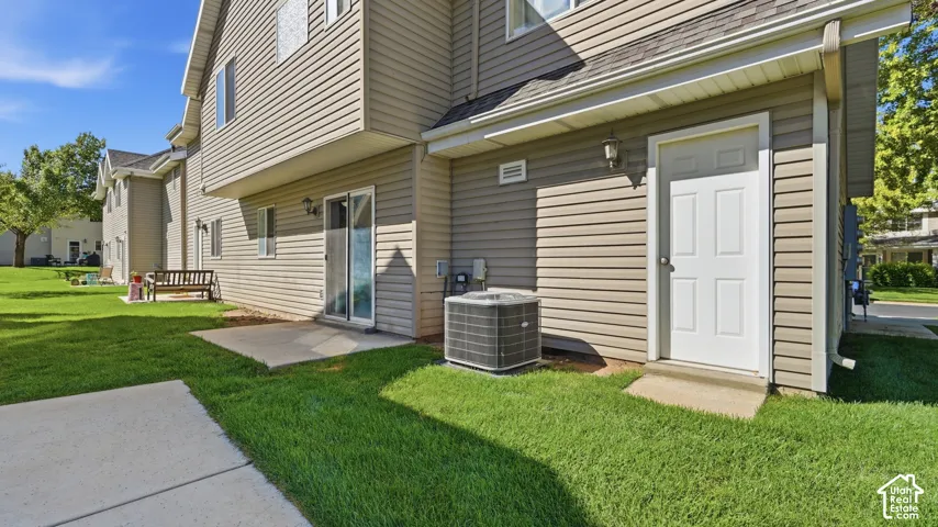 Rear exterior with patio access, mature lawn, and convenient exterior access near the attached garage.
