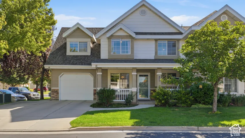 Beautiful two-story residence featuring a covered front porch, attached garage, and a manicured lawn