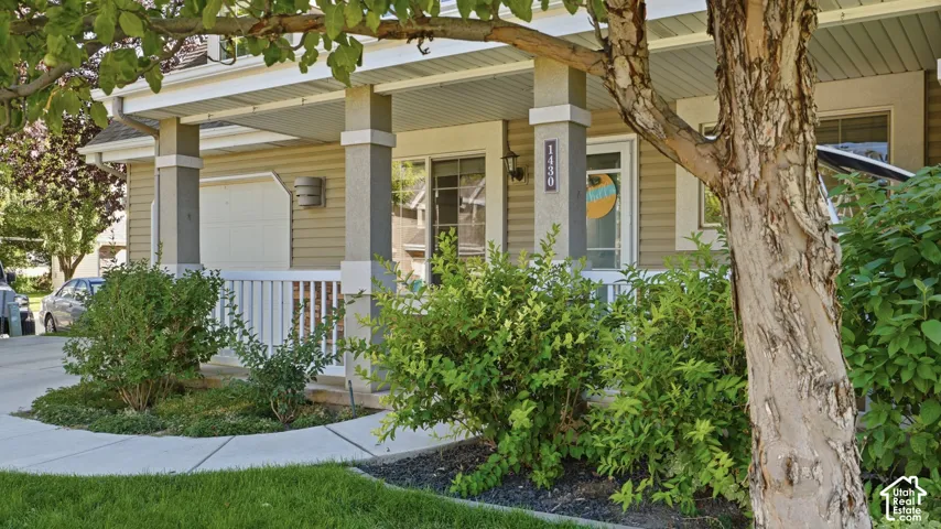 Inviting covered front porch surrounded by mature landscaping and shade trees, creating a welcoming entrance.