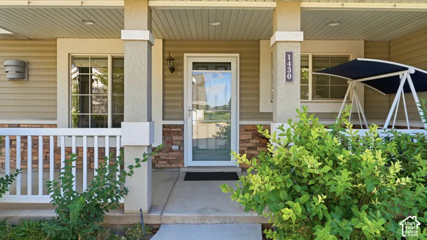Welcoming front porch with architectural columns and stacked stone accents, complemented by horizontal siding and a full-light storm door